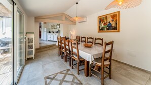 A dining area with a table, chairs, a painting, and a hanging light fixture. - Holiday Home 'Saumane, Grande Bergerie' with Shared Pool, Wi-Fi and Air Conditioning (Saumane-de-Vaucluse)