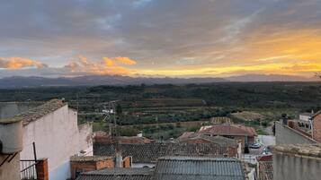 A view of terraced fields and a mountainous landscape during sunset.