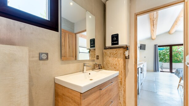 Un baño moderno con tocador de madera, un espejo grande y una zona de ducha visible.