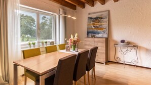 A dining area with a wooden table, green chairs, a vase of flowers, and a painting on the wall. - Apartment 2 in Haus Böhler on the island of Reichenau with Lake View, Terrace and Garden (Reichenau)