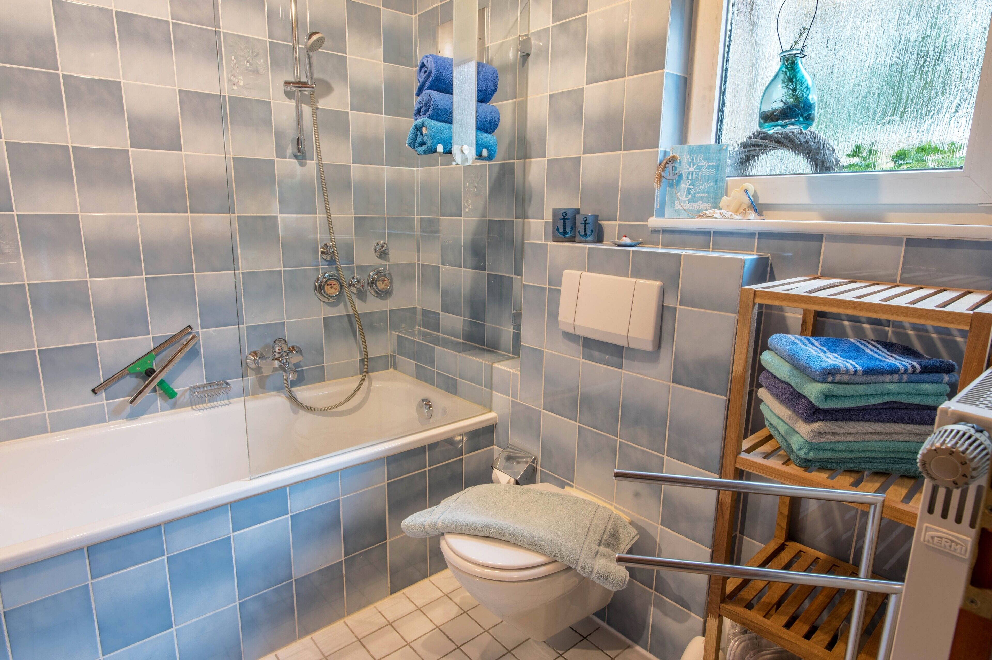 Ein Badezimmer mit Badewanne, Toilette, Dusche und einem Fenster mit Blick ins Freie.