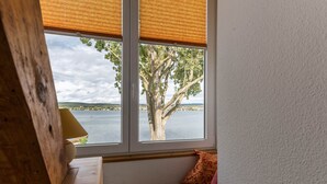 Une pièce dotée d’une grande fenêtre donnant sur un arbre et une étendue d’eau.