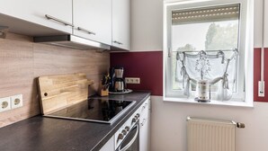 Une cuisine moderne avec un plan de travail noir, des appareils électroménagers en acier inoxydable et une fenêtre agrémentée de rideaux.