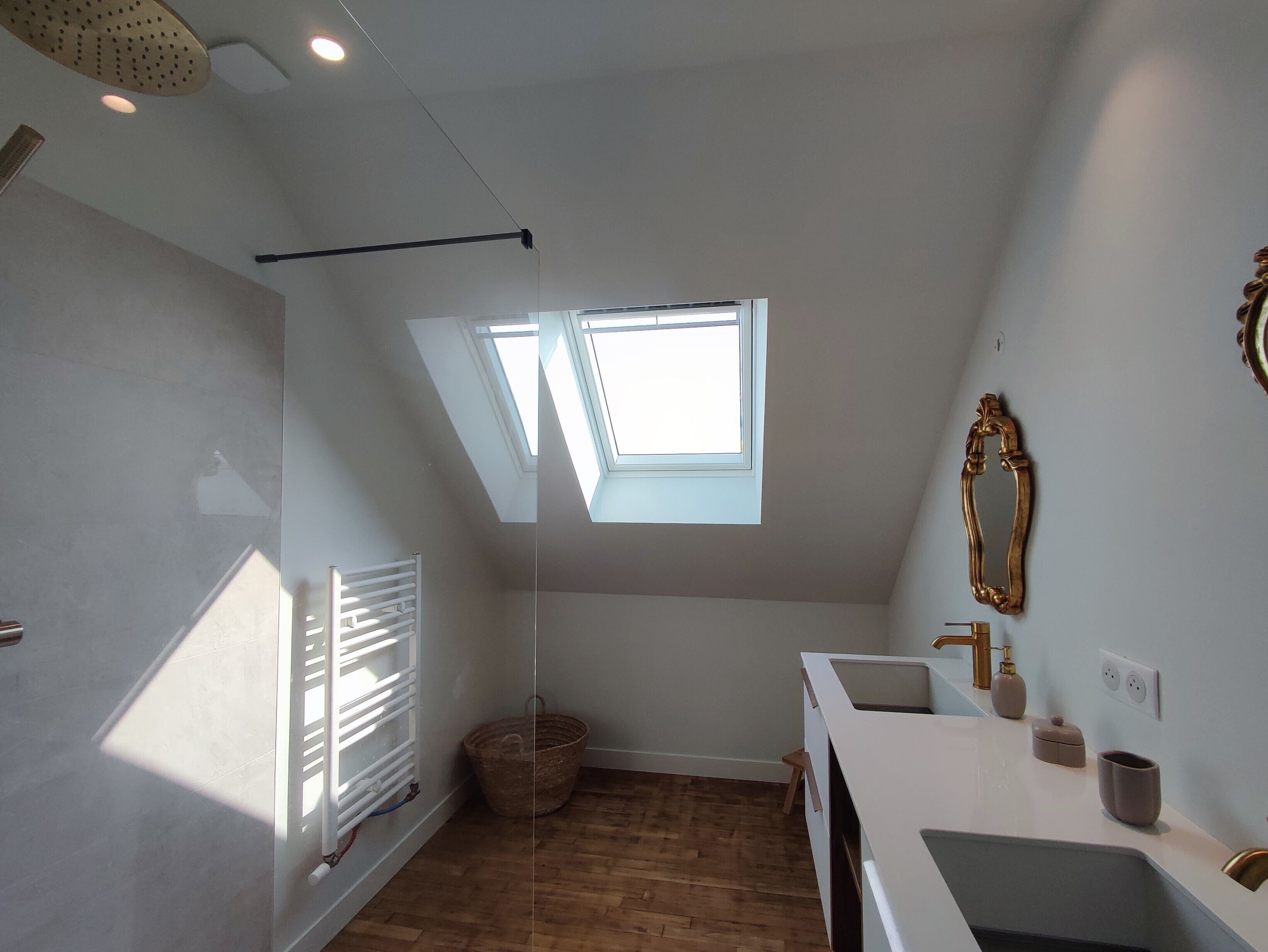 A modern bathroom with a skylight, a large mirror, and a white sink.