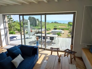Una sala de estar moderna con un amplio ventanal corredero que da a un patio exterior.