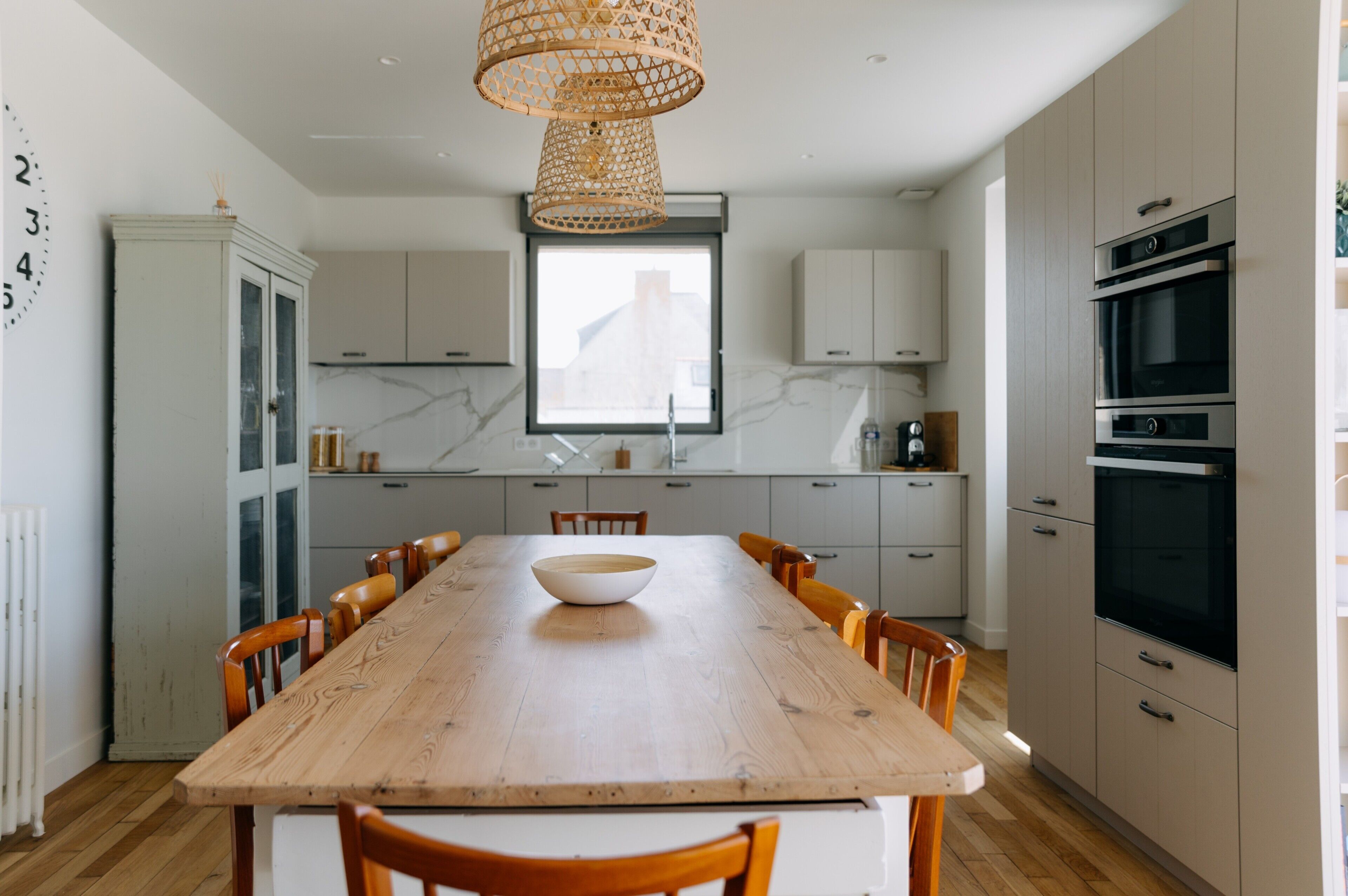 A modern kitchen with a wooden dining table, cabinets, and a built-in oven.