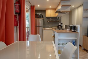 Une cuisine moderne dotée d’appareils électroménagers en acier inoxydable, de meubles en bois et d’une table à manger blanche.