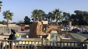 A water feature with a waterfall, palm trees, and a fenced area.