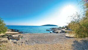 A rocky beach with clear blue water and a distant island. - Beautiful apartment in Rogoznica (Rogoznica)