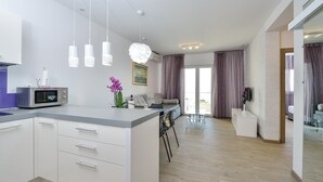 A modern kitchen with a built-in microwave, a dining area with a glass table, and a living space with a sofa and curtains. - Beautiful apartment in Rogoznica (Rogoznica)