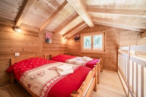 Eine Holzhütte mit zwei Betten, einem Fenster und einer Holzbalkendecke.