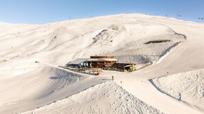 A snow-covered mountain with a wooden lodge and ski lift in the background.