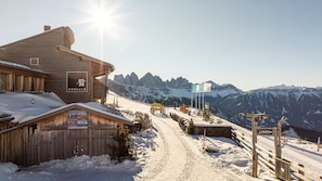 A wooden building with a sign reading 'ROSSALM' and a ski slope in the background.