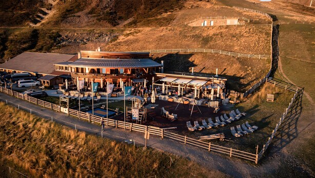 An outdoor restaurant with a patio area, seating, and a view of the surrounding landscape.