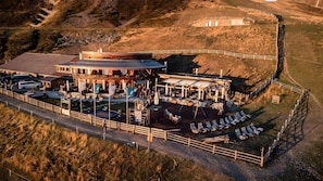 Um restaurante ao ar livre com área de terraço, mesas e vista para a paisagem circundante.