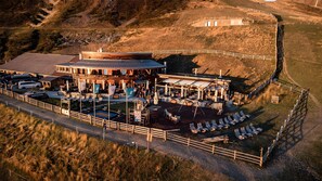 An outdoor restaurant with a patio area, seating, and a view of the surrounding landscape.