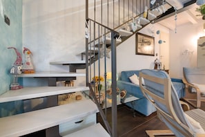 Eine Treppe mit Geländer, ein blaues Sofa und ein Holzstuhl.