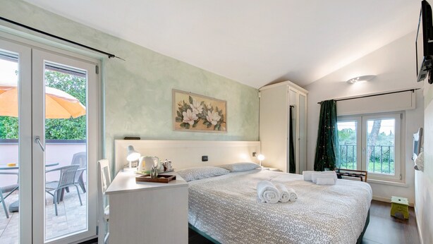 A bedroom with a bed, a desk, a chair, and a window with an umbrella outside.