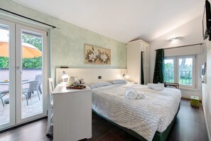 Une chambre à coucher avec un lit, un bureau, une chaise et une fenêtre donnant sur l’extérieur, où se trouve un parapluie.