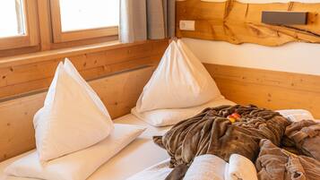 Una stanza accogliente con pareti in legno, un letto con cuscini bianchi, una coperta e una testiera in legno.