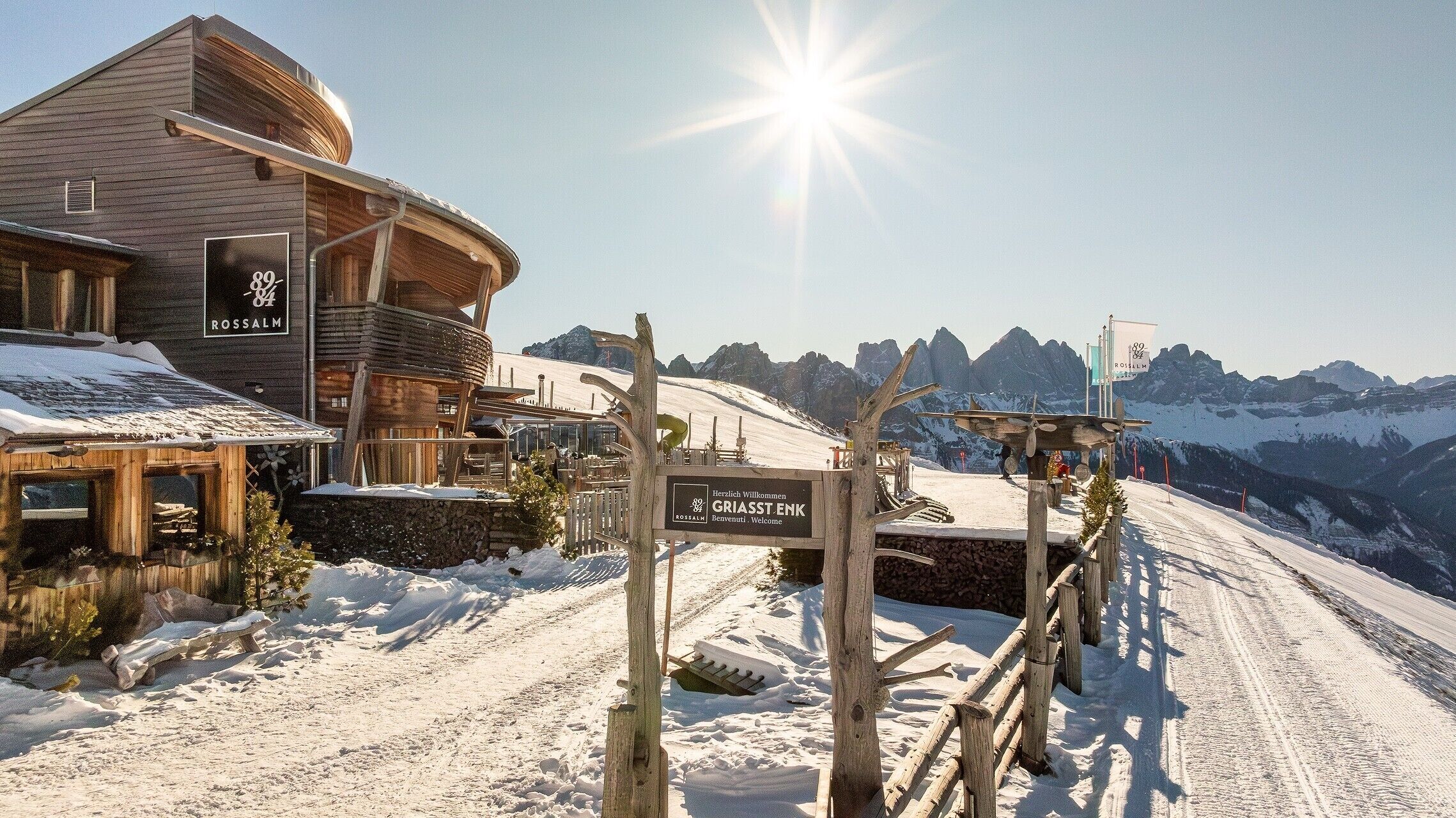 Un edificio in legno con un cartello che recita 'GRIASST-ENK' e 'ROSSALM' sullo sfondo.