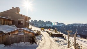 A wooden building with a sign reading 'ROSSALM' and a ski slope in the background. - Room 'Panorama Room 2' with Shared Terrace, Shared Garden and Wi-Fi (Brixen)