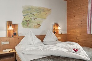 Ein Schlafzimmer mit einem Bett, zwei Nachttischen, einer Wandlampe und einem Bild von Kühen auf einer Farm.
