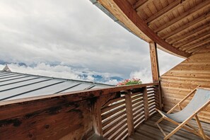 A wooden balcony with a metal roof, wooden railings, and a chair. - Room 'Panorama Room 2' with Shared Terrace, Shared Garden and Wi-Fi (Brixen)