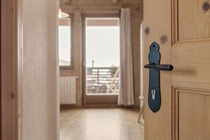 A wooden door with a metal handle and a keyhole, leading to a room with a view of a balcony. - Room 'Panorama Room 2' with Shared Terrace, Shared Garden and Wi-Fi (Brixen)