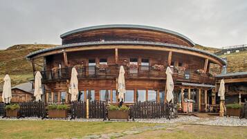 Un edificio in legno dal design circolare, con posti a sedere all'aperto, ombrelloni e composizioni floreali.