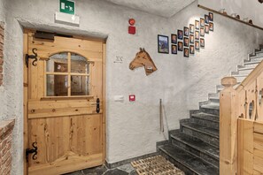 A wooden door with a window, a wall-mounted horse head clock, and a staircase with a wooden handrail. - Room 'Panorama Room 2' with Shared Terrace, Shared Garden and Wi-Fi (Brixen)