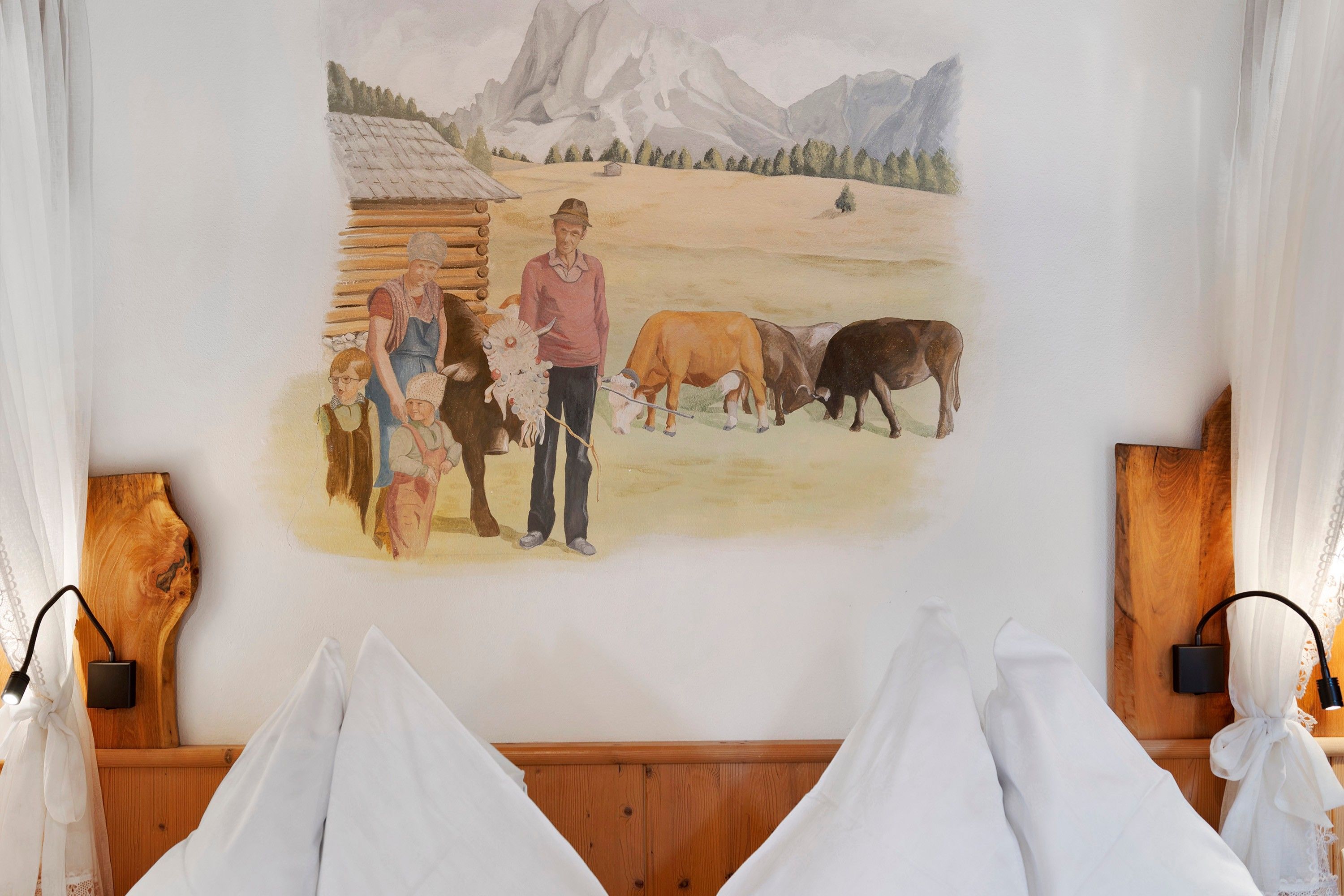 Ein Zimmer mit einem hölzernen Kopfende, einem Landschaftsbild und einem Holzsideboard.