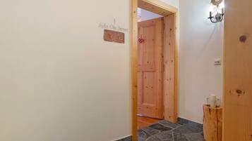 Un pasillo con puerta de madera, suelo de piedra y una pequeña placa en la pared.