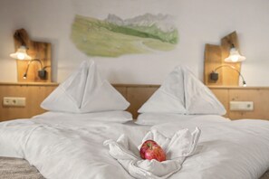 Habitación de hotel con una cama, almohadas, una colcha y dos manzanas sobre la cama.