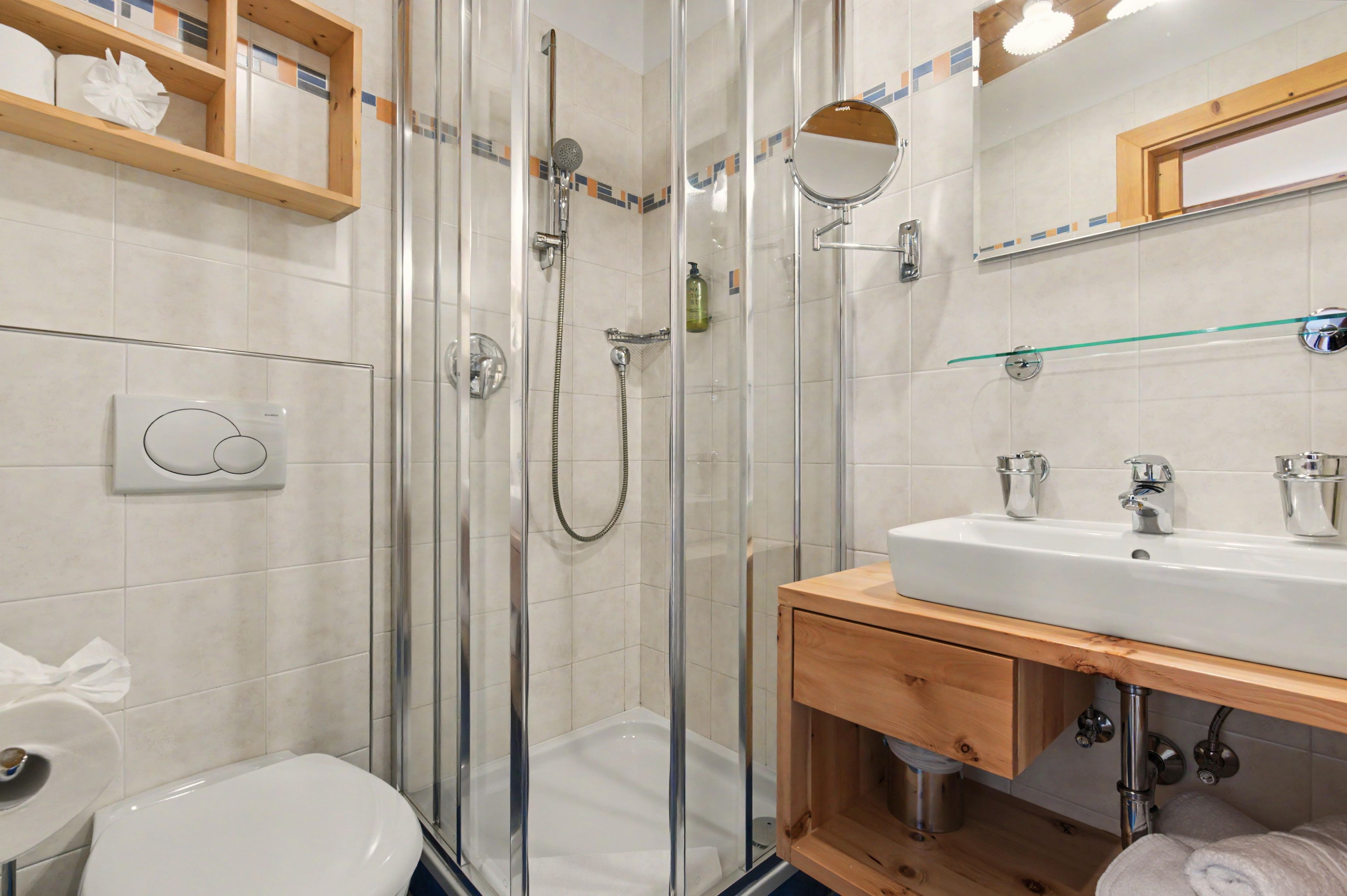 A modern bathroom with a glass-enclosed shower, a white sink, and a wooden vanity.