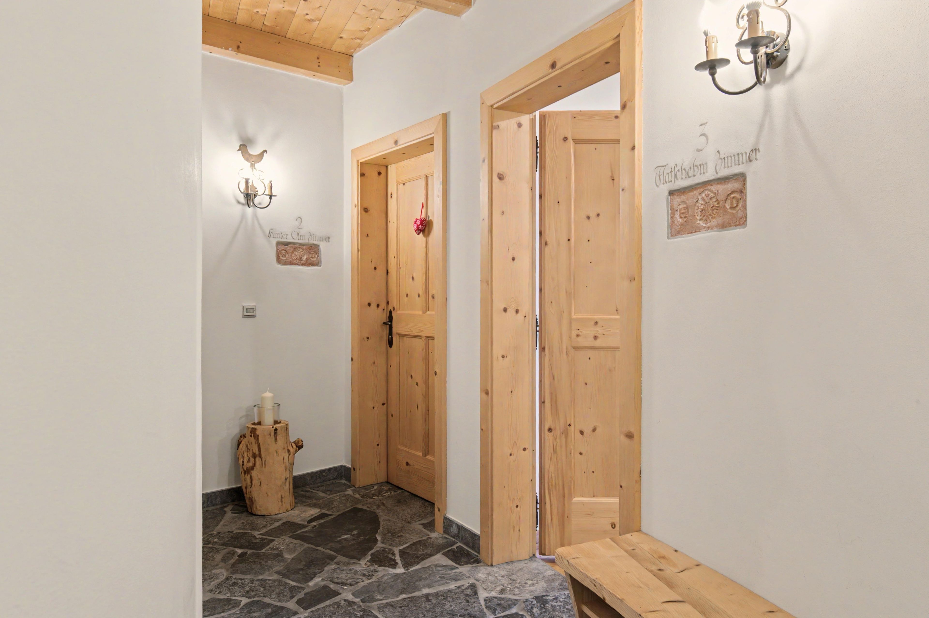 A hallway with wooden doors, a stone floor, and a bench.