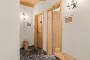 En hall med trädörrar, ett stengolv och en bänk.