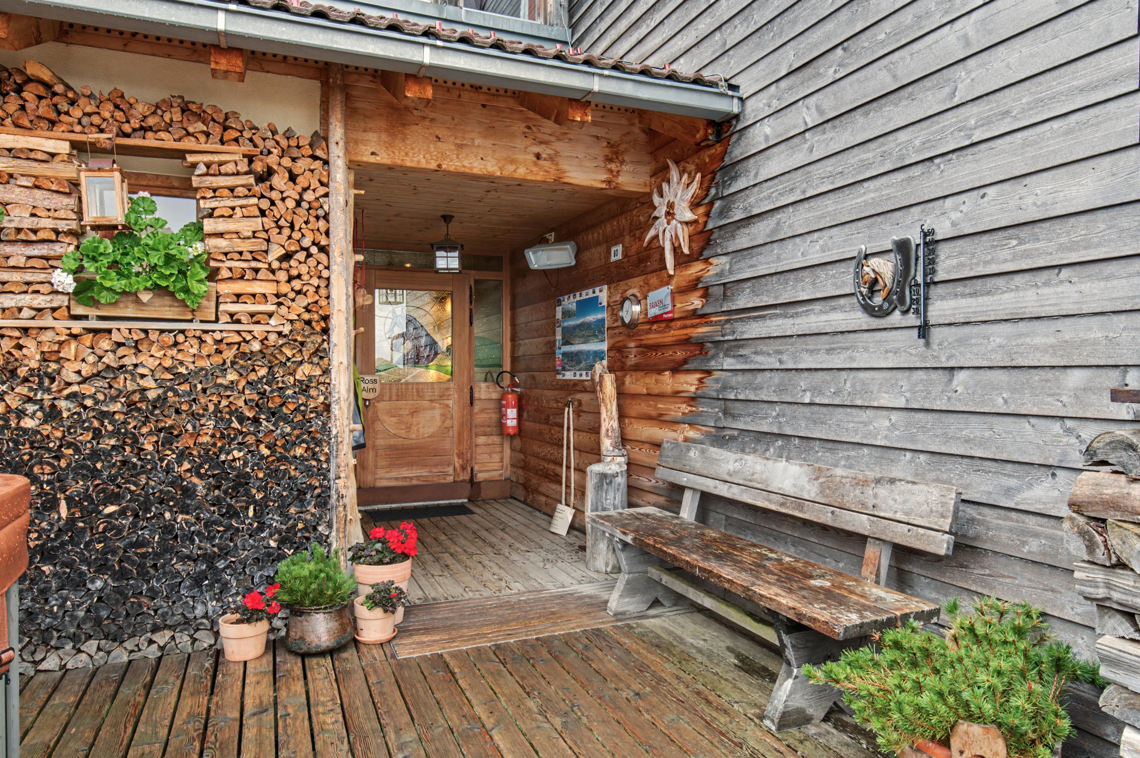 A wooden building with a wooden door, a bench, and potted plants.