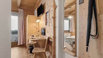Una habitación de madera con escritorio, silla y cama.