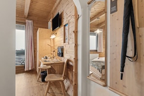 Ein Zimmer aus Holz mit einem Schreibtisch, einem Stuhl und einem Bett.