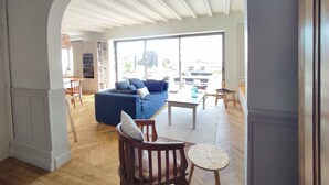 An open-plan living area with a sofa, chairs, a coffee table, and a dining area with a table and chairs. - La Perle, 6 guests, 180° sea view, jacuzzi (Plobannalec-Lesconil)