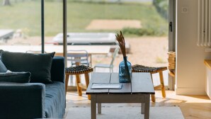 A modern living room with a sofa, a coffee table, and a view of the outdoors. - La Perle, 6 guests, 180° sea view, jacuzzi (Plobannalec-Lesconil)