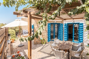 An outdoor patio with wicker furniture, a stone wall, and a pergola. - Holiday Home 'Kalliope' with Sea View, Wi-Fi and Air Conditioning (Gennadi - Rhodos - Dodekanese)