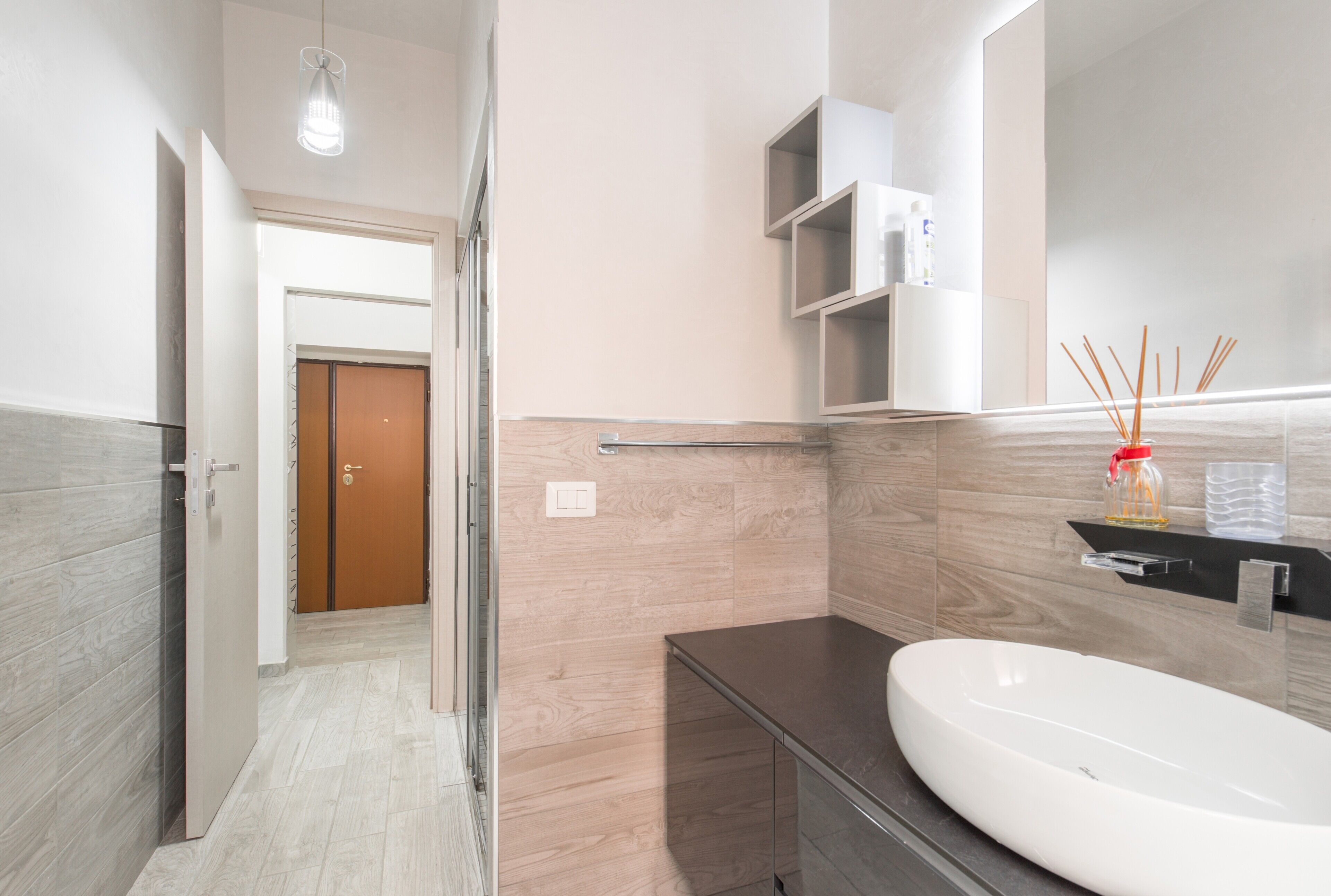A modern bathroom with a large sink, a mirror, and a door leading to another room.