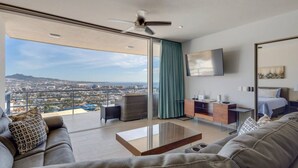 Uma sala de estar moderna com uma grande porta de vidro que dá para uma varanda com vista para a cidade.