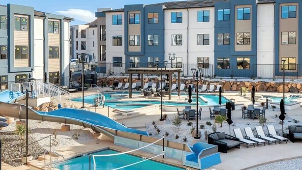 Uma área de piscina com várias piscinas, espreguiçadeiras e um tobogã.