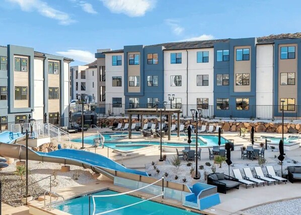 A pool area with multiple pools, lounge chairs, and a water slide.