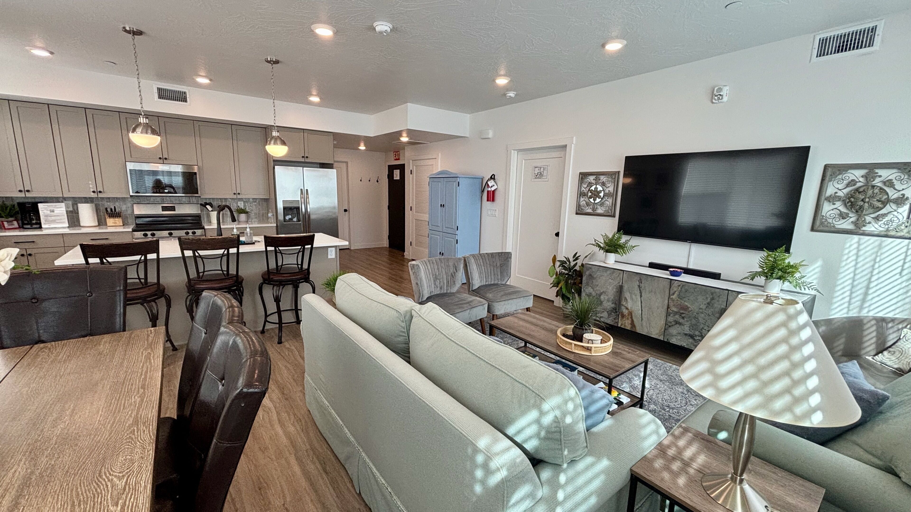 A modern living room with a sofa, armchairs, a coffee table, and a TV.