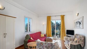 A living room with a sofa, armchair, TV, and a cabinet. - Holiday Home 'Ca' Del Sole' with Sea View, Private Garden and Wi-Fi (Civezza)