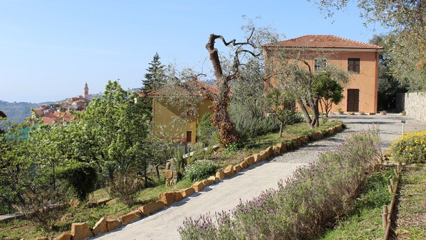 A hillside property with a paved path, a building with a red-tiled roof, and a view of a distant town. - Holiday Home 'Ca' Del Sole' with Sea View, Private Garden and Wi-Fi (Civezza)